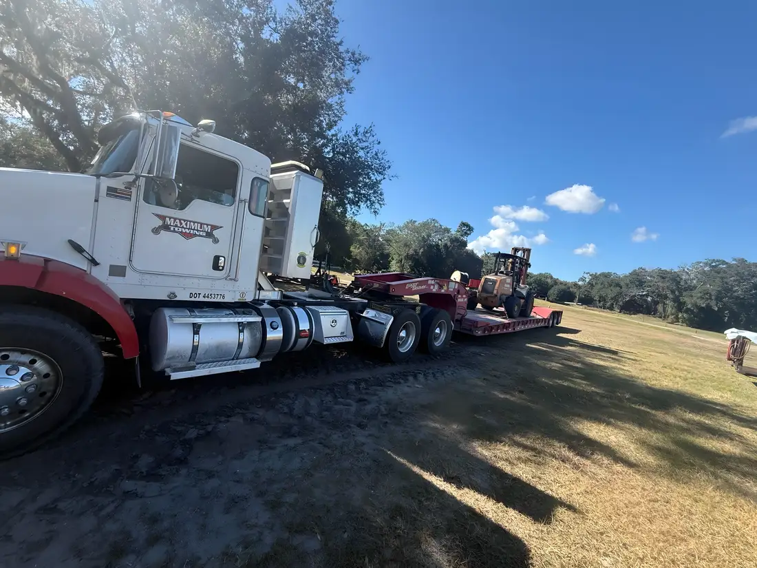 Forklift on a lowboy behind a Kenworth tractor